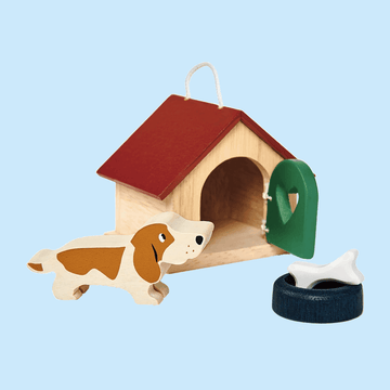 Wooden toy set featuring a dog, a red-roofed doghouse with a green door, a food bowl, and a white bone, all placed on a light blue background.