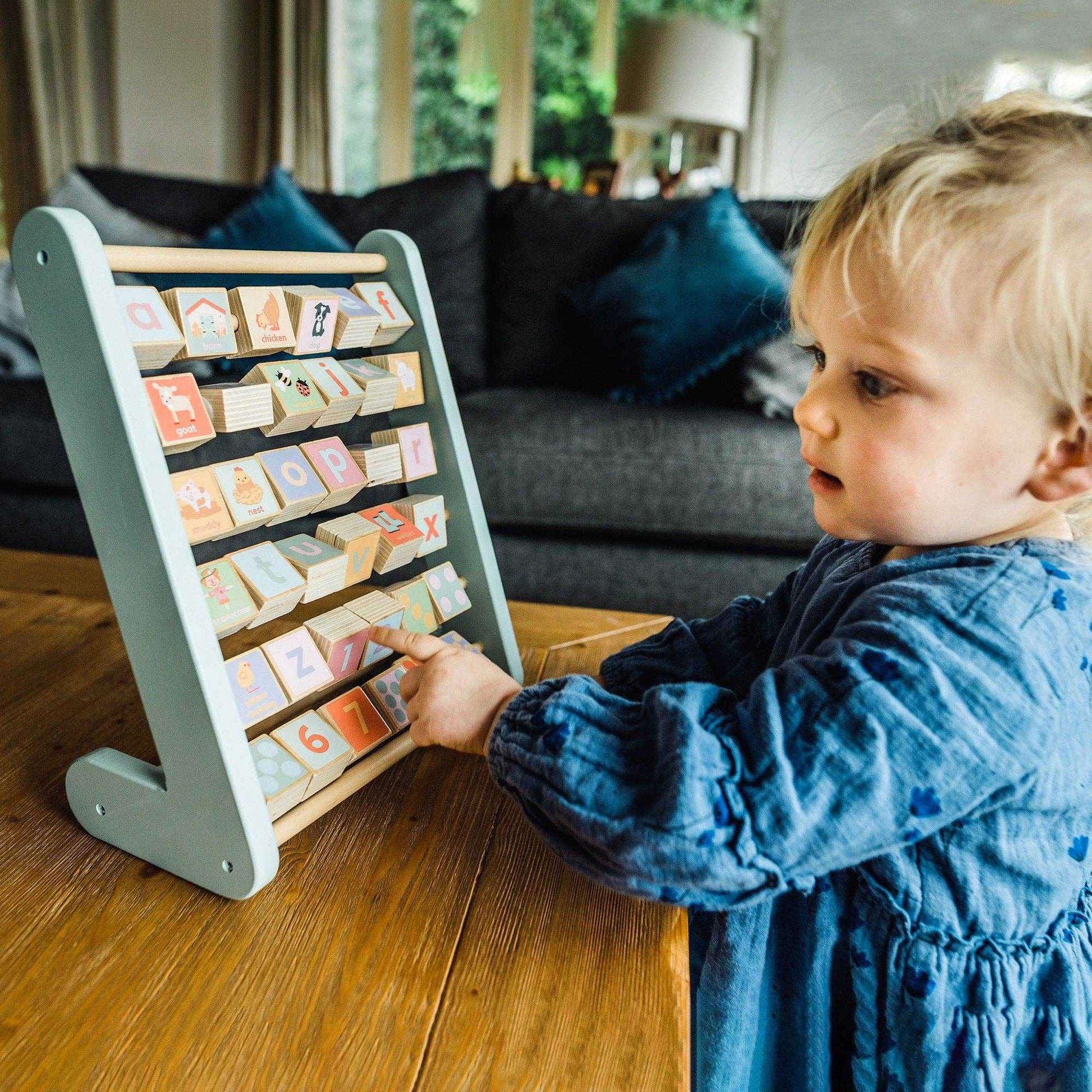 Toddler playing with Farm Animal Alphabet Abacus, a wooden educational toy designed to teach ABCs and counting through play.